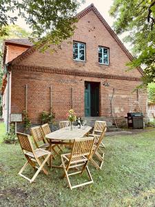 a wooden table and chairs in front of a brick house at Wald- und Seeidyll im historischen Forsthaus in Neuruppin
