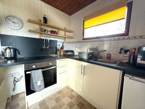 Una cocina con gabinetes blancos y un reloj en la pared. en Equinox Cabin, en Torlundy 22 fotos más