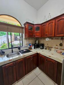 Una cocina con gabinetes de madera y un fregadero. en Casa carretera sur, en Managua