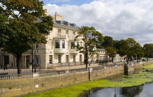 a large white building next to a river at Bedford Swan Hotel and Thermal Spa in Bedford