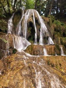 a waterfall in the middle of a forest with rocks at Chalupa Kalameny in Kalameny
