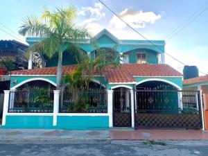 a blue house with a gate and a palm tree at Casa-hogar moises in Los Tres Brazos