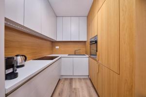- une cuisine avec des placards blancs et un mur en bois dans l'établissement The Stylish Studio, à Bratislava