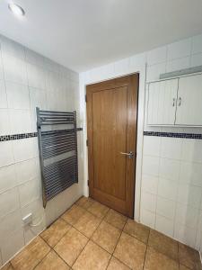 a bathroom with a wooden door and a tiled wall at Pears Suite - 1 Bedroom - Sleeps 2 in Whitehaven