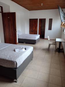 a bedroom with two beds and a table and a desk at Hotel Lili Popayán - Sede 2 in Popayan