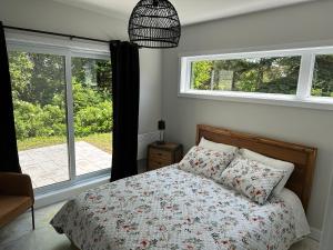 a bedroom with a bed and two windows at Kabin Kamouraska 2 in Rivière-Ouelle