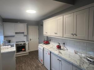 a kitchen with white cabinets and marble counter tops at Champions View in Clonakilty