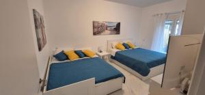 a bedroom with two beds with blue and yellow pillows at Vila Amore in Asprovalta