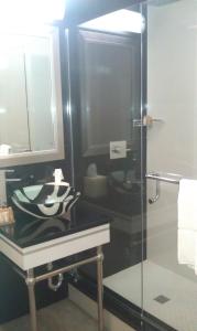 a bathroom with a glass shower and a sink at Lotus Boutique Inn and Suites in Ormond Beach