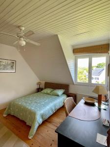 a bedroom with a bed and a ceiling fan at Maison aux camélias in Locquénolé