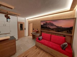 a living room with a red couch and a painting at Dolomiten Home in Villnoss
