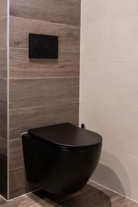 a black toilet in a bathroom with a wall at The White House Apartment in Tholen