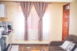 a living room with a window with curtains at Serene STUDIO apartment in Machakos in Machakos