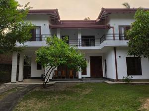 a large white house with a tree in front of it at Air Ray Homestay in Negombo
