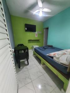 ein Schlafzimmer mit einem Bett und einem Fernseher an der Wand in der Unterkunft Pousada Maranata in Guarujá