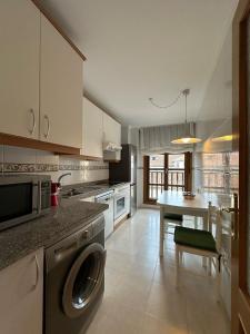 a kitchen with a washing machine and a table at Cuevas del Mar in Nueva de Llanes +19 photos