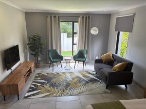 a living room with a couch and chairs and a tv at Serenity Luxury Guesthouse in Krugersdorp