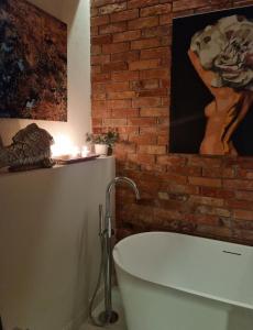 Un baño con una bañera blanca junto a una pared de ladrillo. en Luxury apartment in center town!, en Poznan