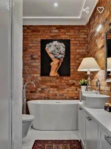 baño con bañera blanca y pared de ladrillo en Luxury apartment in center town!, en Poznan