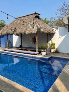 a swimming pool with a straw umbrella and a house at Sandollar in León