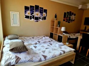 a bed in a bedroom with pictures on the wall at Két Sirály Apartman in Siklós