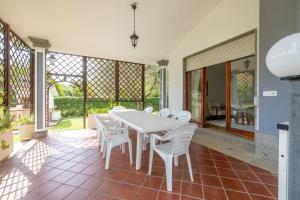 Un comedor con una mesa y sillas blancas. en Spaziosa Villa con piscina, BBQ e campi da tennis, en Casal Palocco