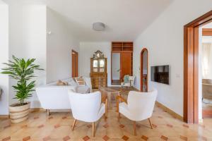Una sala de estar con sillas blancas y una mesa. en Spaziosa Villa con piscina, BBQ e campi da tennis, en Casal Palocco