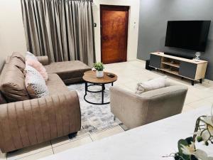 a living room with two couches and a television at Sweet Daisies Apartment in Mbabane