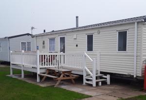 a white mobile home with a porch and a picnic table at Haven Skegness 20 Donna Nook in Skegness