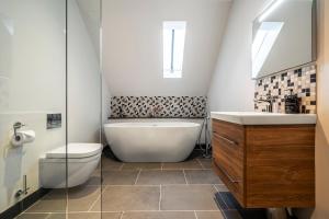 a bathroom with a tub and a toilet and a sink at Holly Tree Cottage in Dornoch