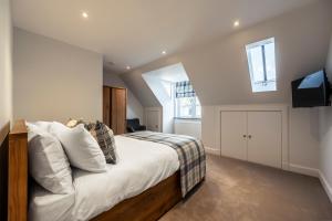 a bedroom with a bed with white sheets and a television at Holly Tree Cottage in Dornoch