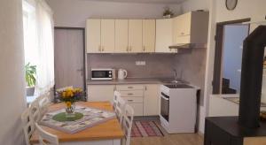 a kitchen with a table with chairs and a kitchen with white cabinets at Chalupa Kalameny in Kalameny