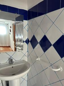un bagno con pareti piastrellate blu e bianche e un lavandino di Hotel Al Manar a Chefchaouen