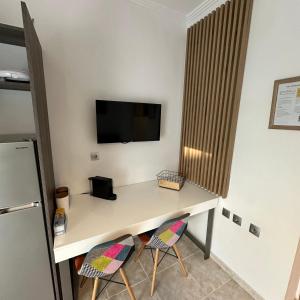 a desk with two chairs and a tv on a wall at R&T Apartments in Kallithea Halkidikis