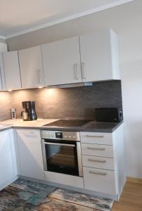 a kitchen with white cabinets and a stove top oven at Schicke FeWo 150m vom Strand kostenlos WLAN großes Schwimmbad Sauna in Cuxhaven