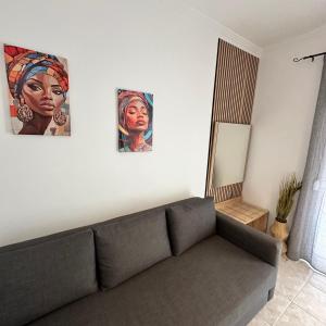 a living room with a couch and two paintings on the wall at R&T Apartments in Kallithea Halkidikis
