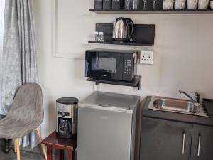 a small kitchen with a microwave and a refrigerator at Lunford Garden Cottage in Rayton