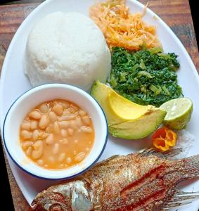 een bord met vis en rijst en een kom bonen bij Alkebulan Farm House in Moshi