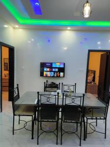 a dining room table with chairs and a tv on the wall at 2 Bedroom Luxury Apartment in Dakar
