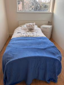 Una cama en una habitación con una manta azul encima. en Quarto single, en Stykkishólmur