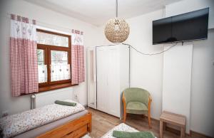 a bedroom with a bed and a tv and a chair at Hostinec pod úbočou in Valaská