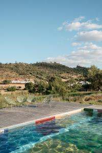 a pool with chairs and a view of a hill at Viva! Farmhouse in Monsaraz