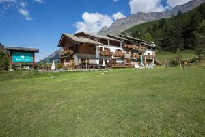 a large building in a field in front of a mountain at Albergo Boule de Neige in Rhêmes-Notre-Dame