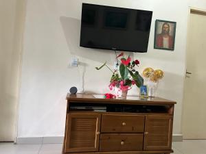 a tv on top of a dresser with flowers on it at Hospeday in Sao Paulo