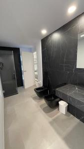 een badkamer met 2 toiletten en een zwarte muur bij apartament in Marbella
