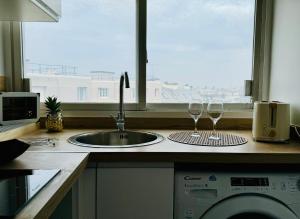 a kitchen counter with a sink and two wine glasses at Cosy flat with view in Asnières-sur-Seine