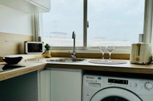 a kitchen with a washing machine and a sink at Cosy flat with view in Asnières-sur-Seine