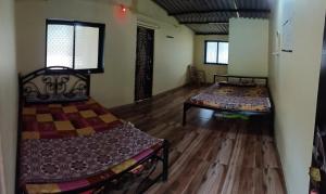 戴维格Pranjal Guest House的客房内设有两张床,铺有木地板,设有窗户。