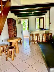 a kitchen with wooden tables and stools in a room at Apto pé na areia de Gamboa do Morro in Cayru