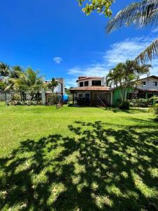 a green yard with a house and palm trees at Apto pé na areia de Gamboa do Morro in Cairu